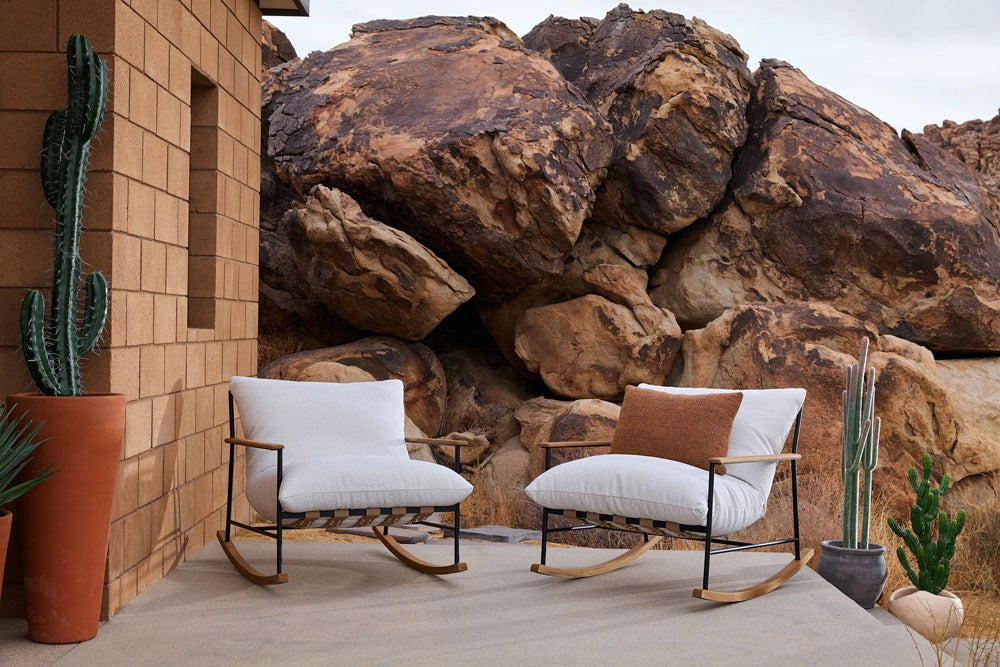 Two Outdoor Vail Rockers with white cushions in front of a rocky landscape.